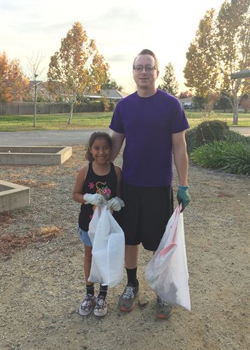 Parent and student picking up trash in the school garden